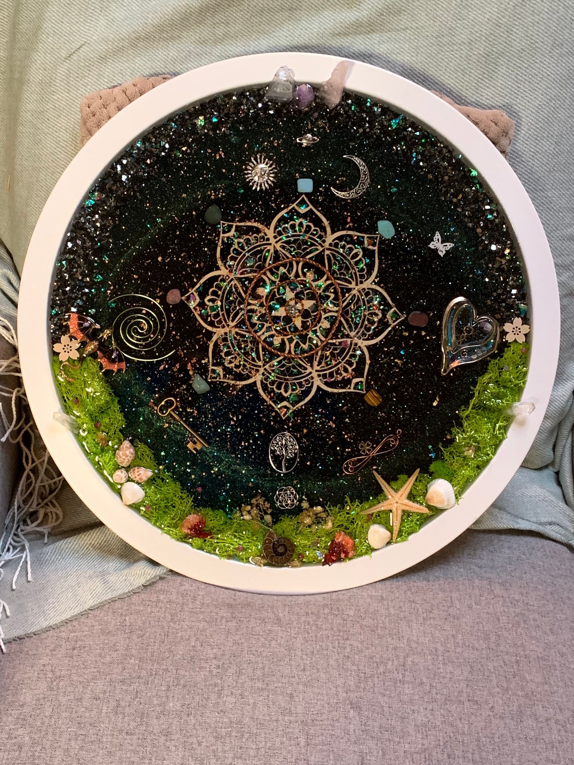 Een rond orgonite-werk met een mandala erop.