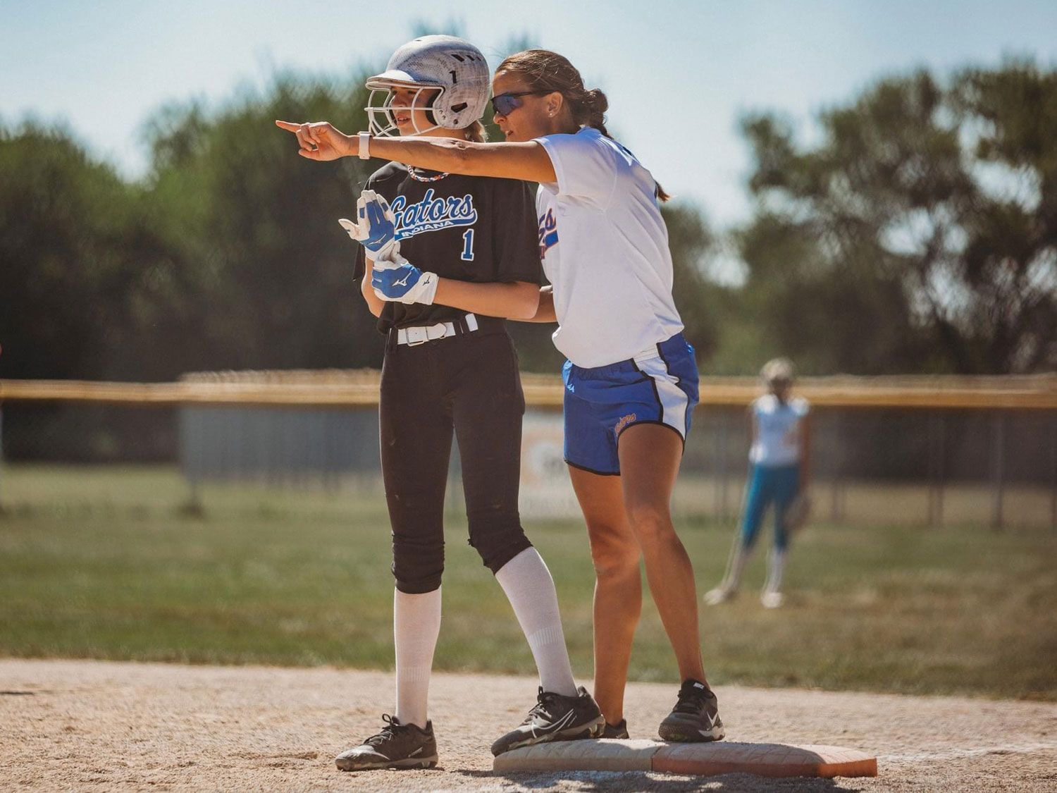 Coach Yo is standing next to a girl on a softball field.