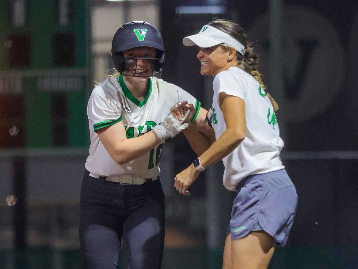Coach Yo and player are hugging each other on a baseball field.