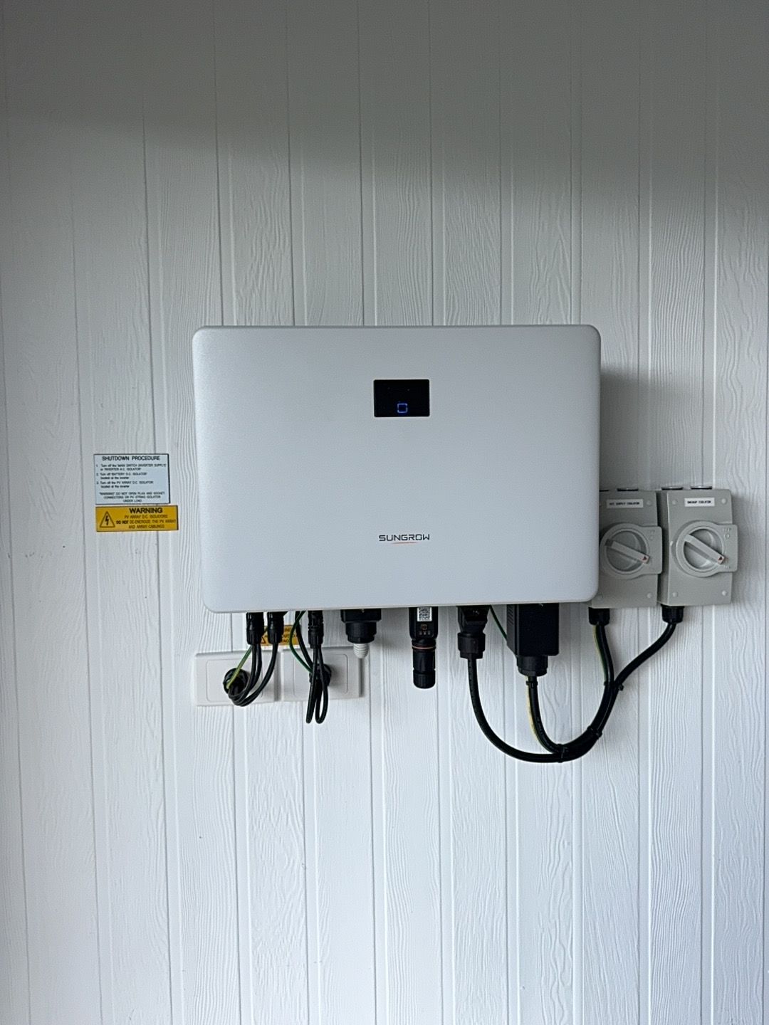 A Solar Panel Inverter Is Mounted On A White Wall — Rid-Arc Electrical In Tamworth, NSW