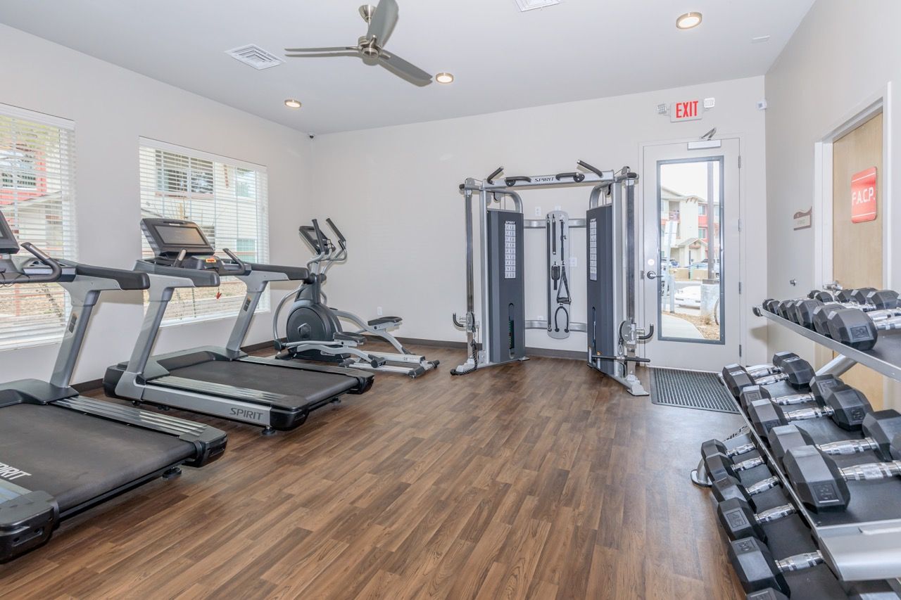 Indoor fitness center with treadmills, elliptical, weight rack, and cable machine.