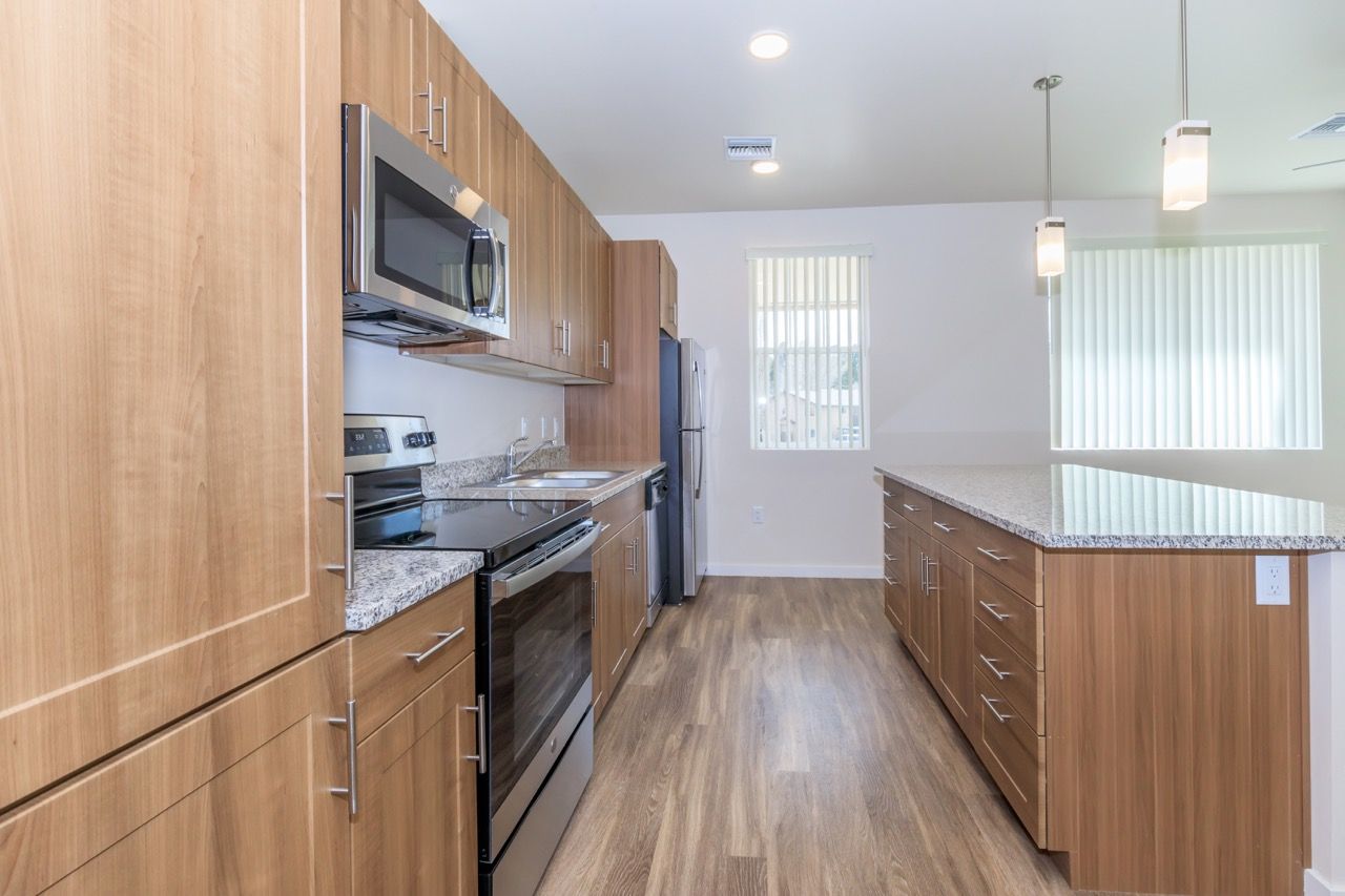 Open-concept kitchen with wood cabinets, granite countertops, and stainless steel appliances.