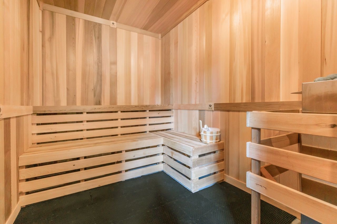 Wood-paneled communal sauna with tiered benches and a bucket.