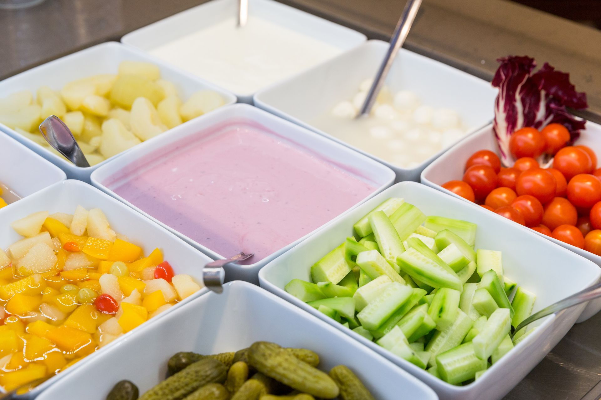 Buffet tray with assorted fruit, vegetables, pickles, and pink yogurt dip