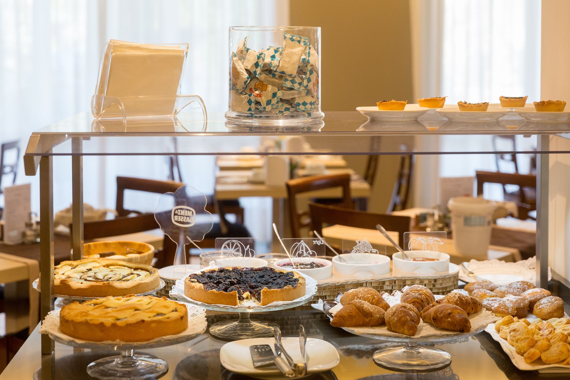 Buffet table with pastries, fruit, and desserts in a bright dining area