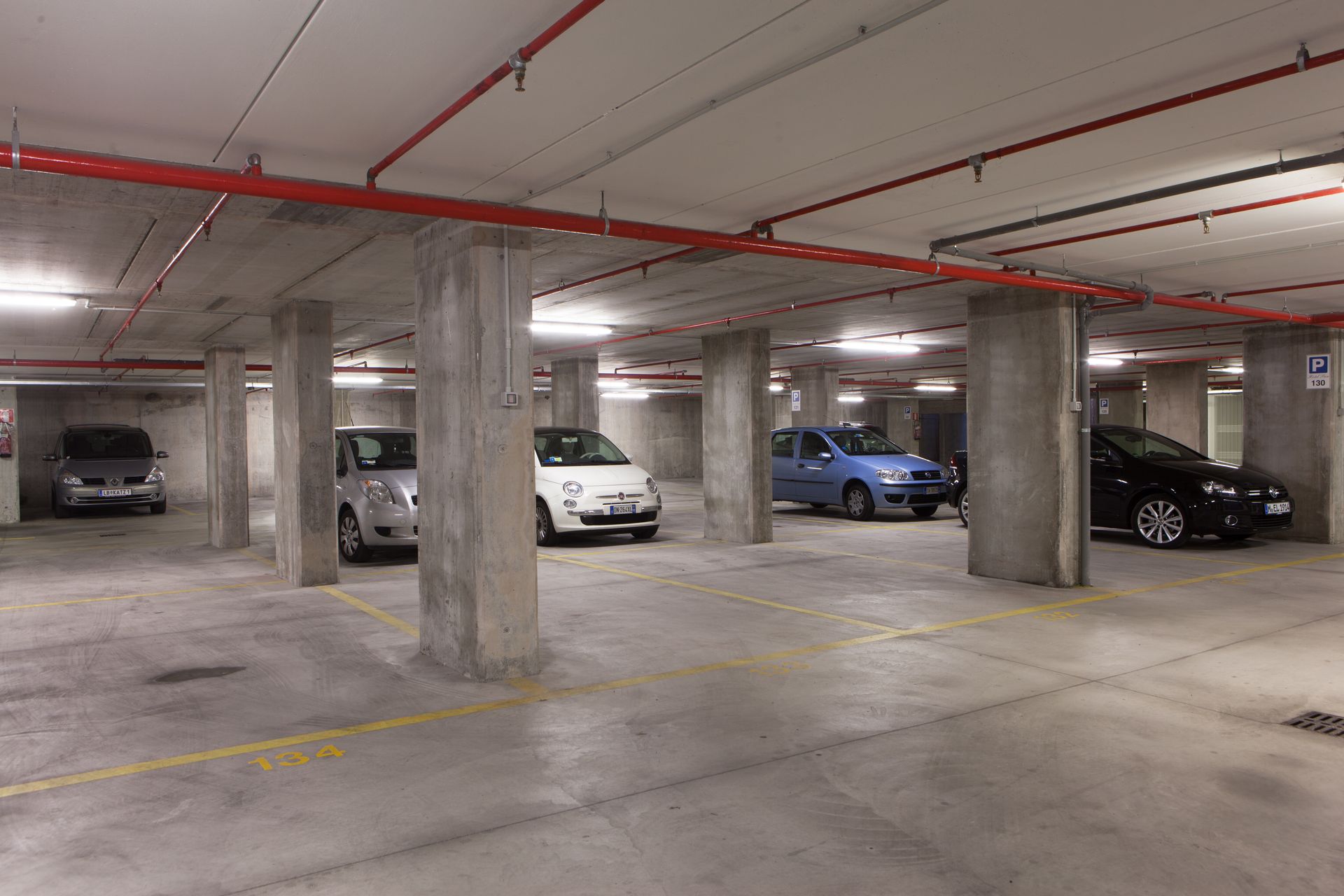 Underground parking garage with several parked cars and concrete pillars