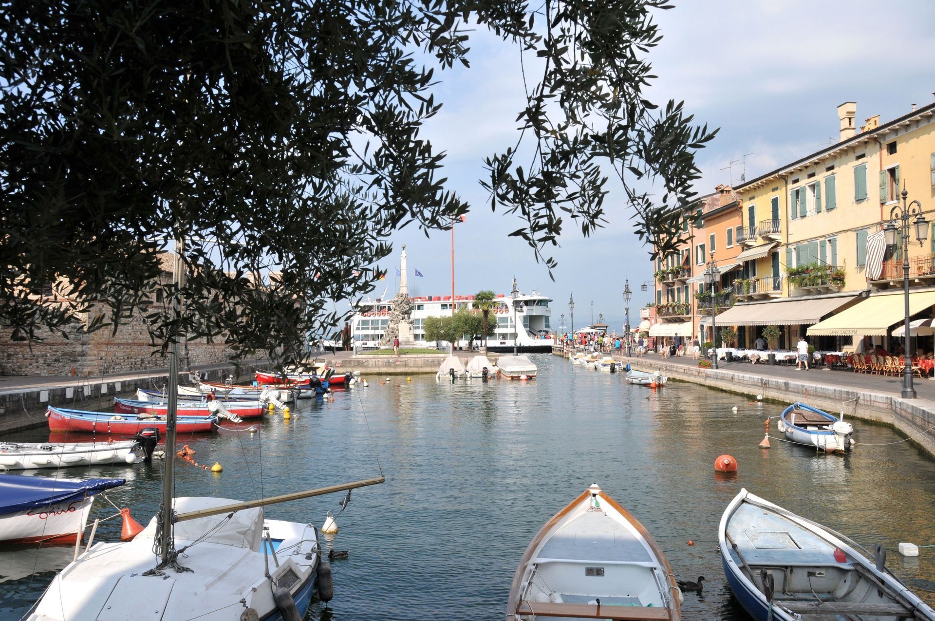 Boote, die in einem ruhigen Hafen neben pastellfarbenen Gebäuden am Wasser und Straßencafés in der Abenddämmerung