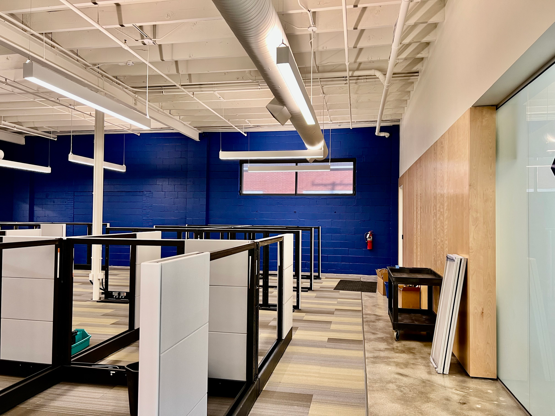 A large empty office with cubicles and a blue wall.