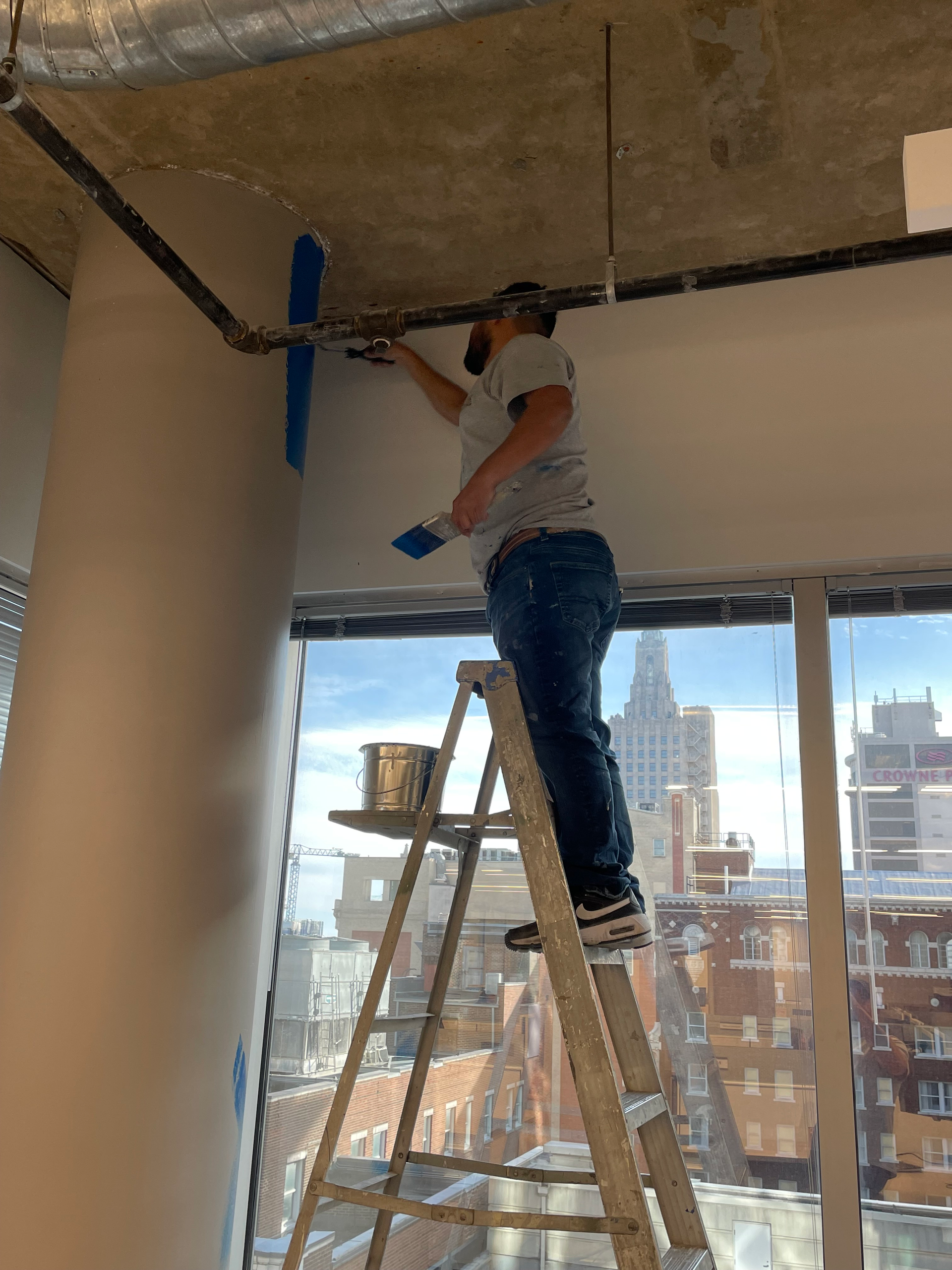 A man is standing on a ladder painting a wall.
