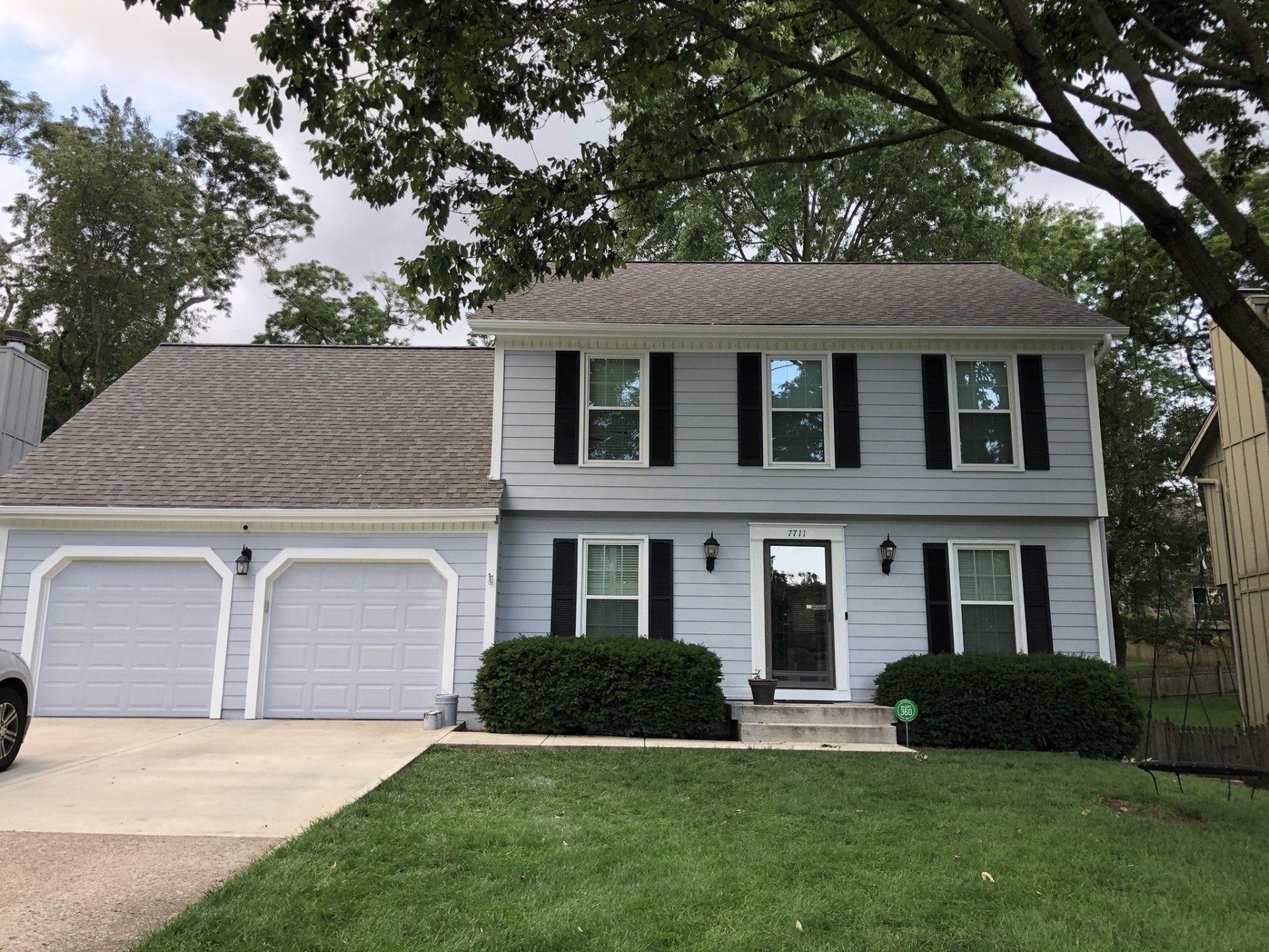 A white house with black shutters and a car parked in front of it