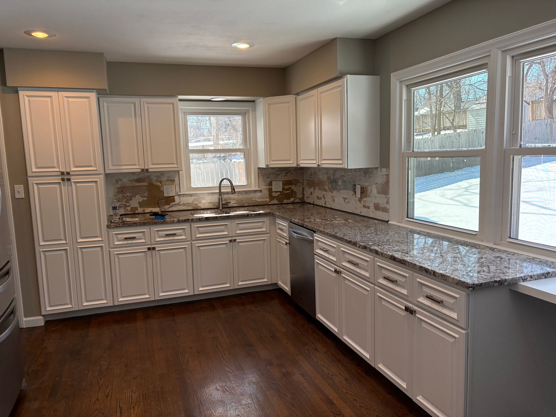 A kitchen with white cabinets and granite counter tops.