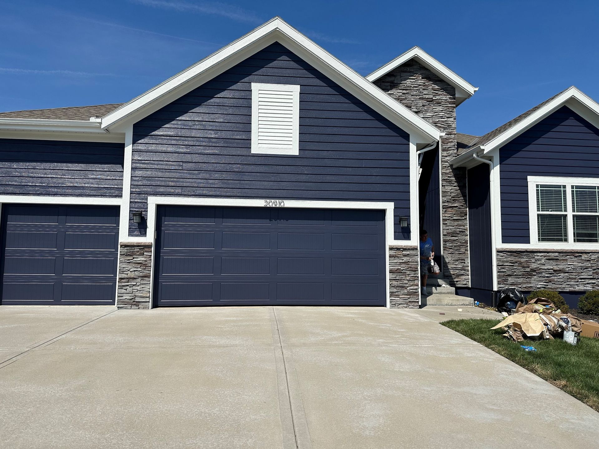 A blue house with two garage doors and a concrete driveway.