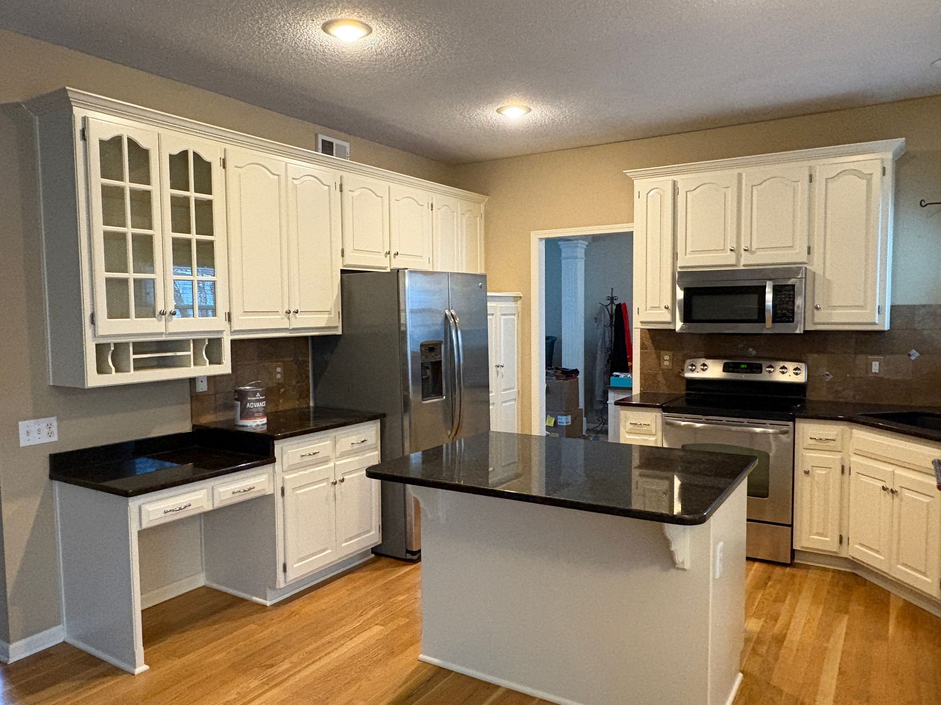 A kitchen with white cabinets , stainless steel appliances , granite counter tops and a large island.