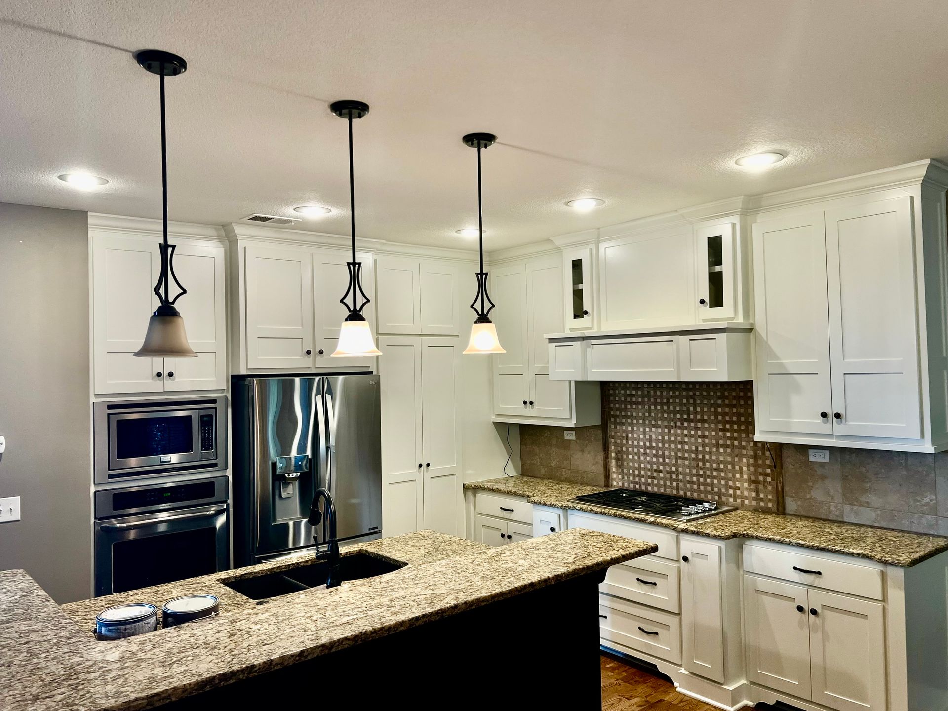 A kitchen with white cabinets , granite counter tops , and stainless steel appliances.