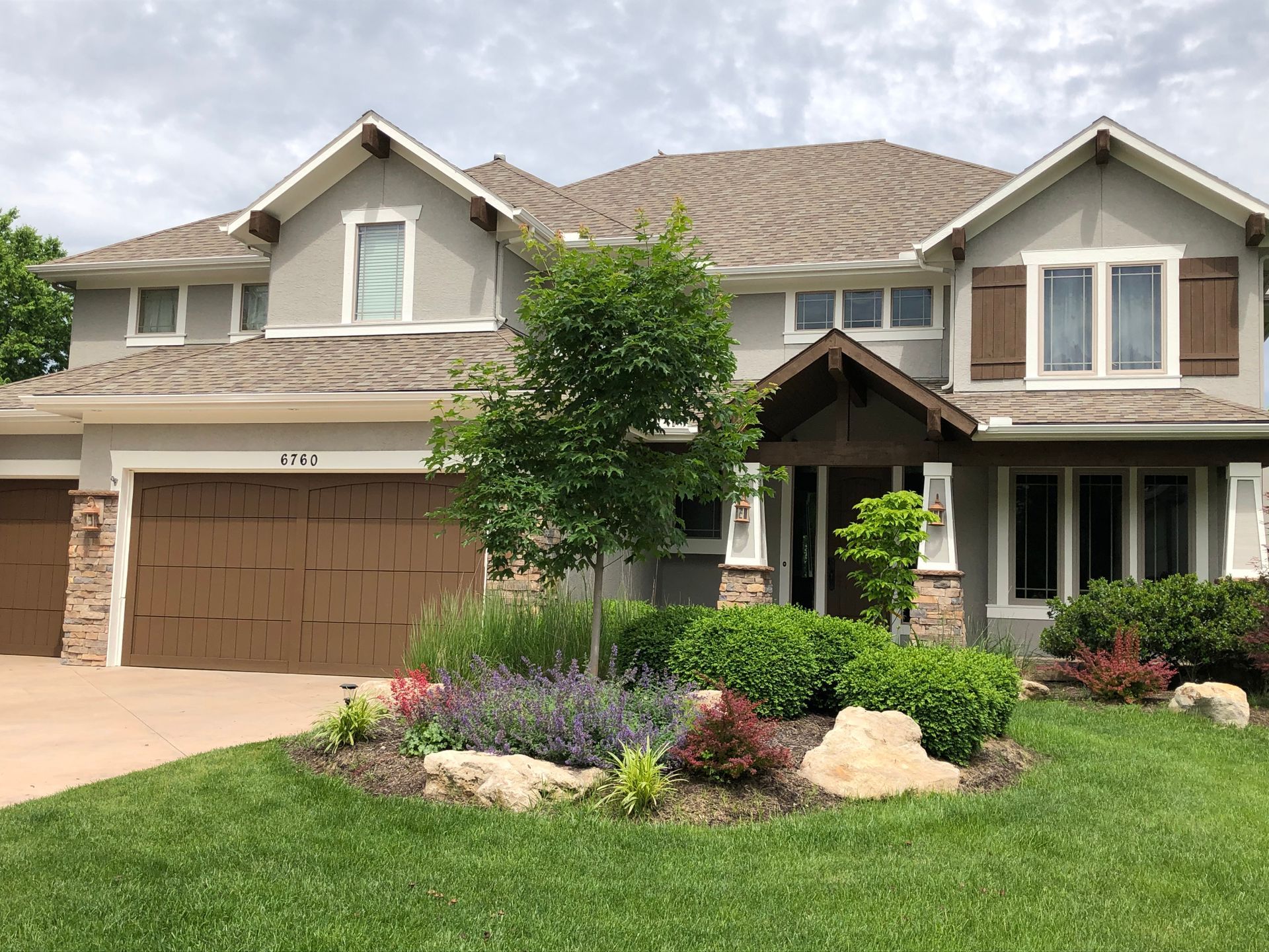 A large house with a brown garage door and a lush green lawn