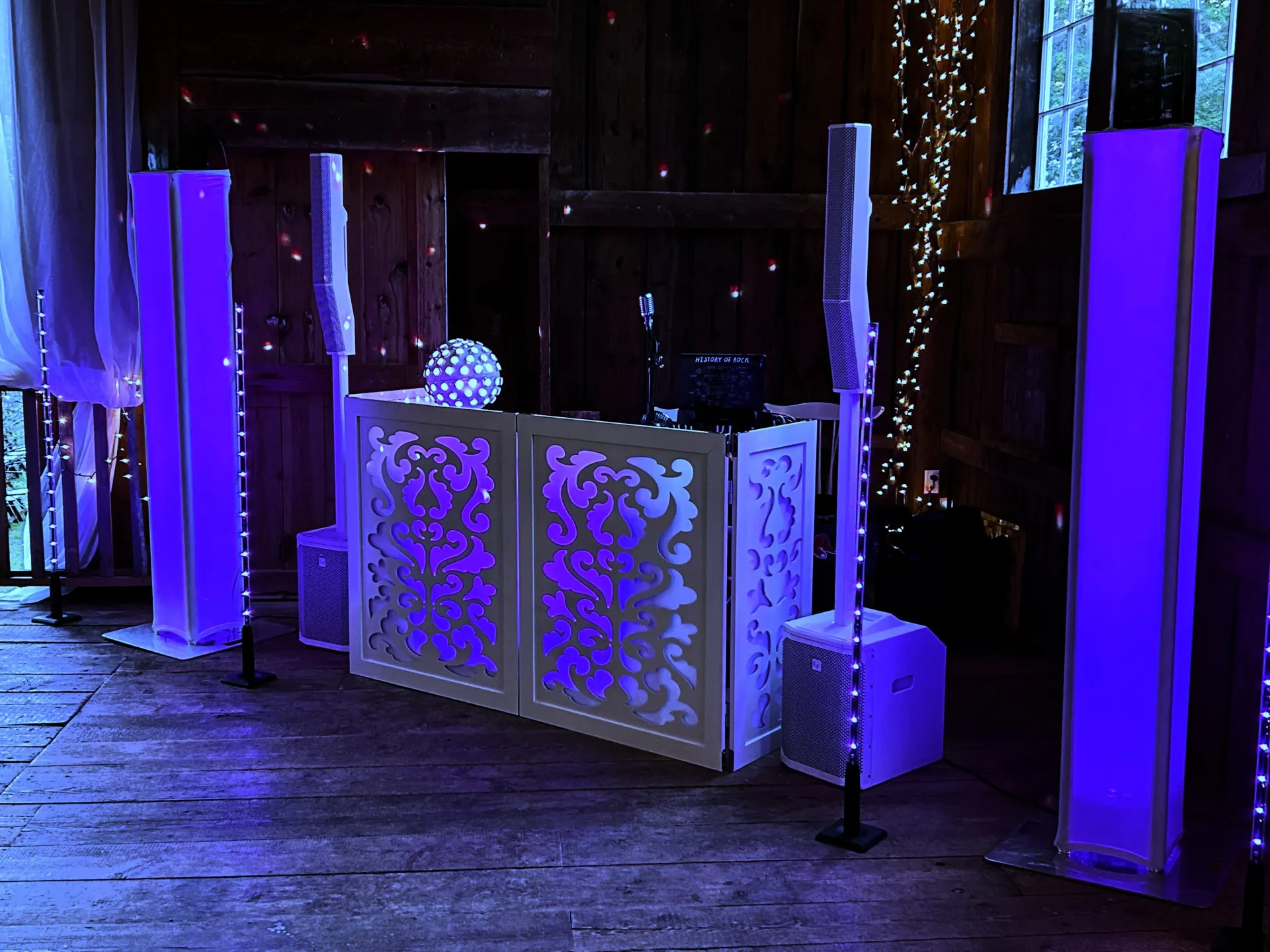 A dj booth is lit up with purple lights in a dark room.