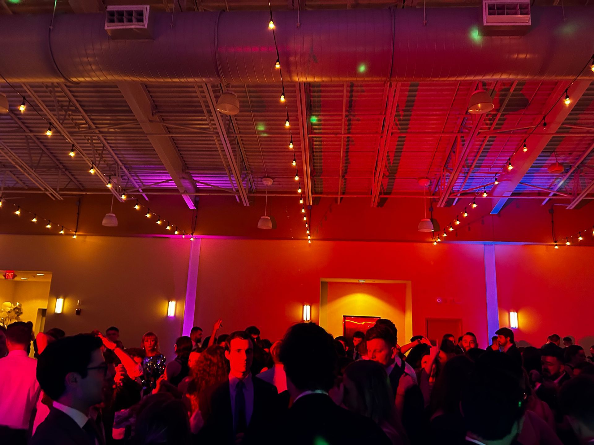 a crowd of people are dancing in a room with red and blue lights
