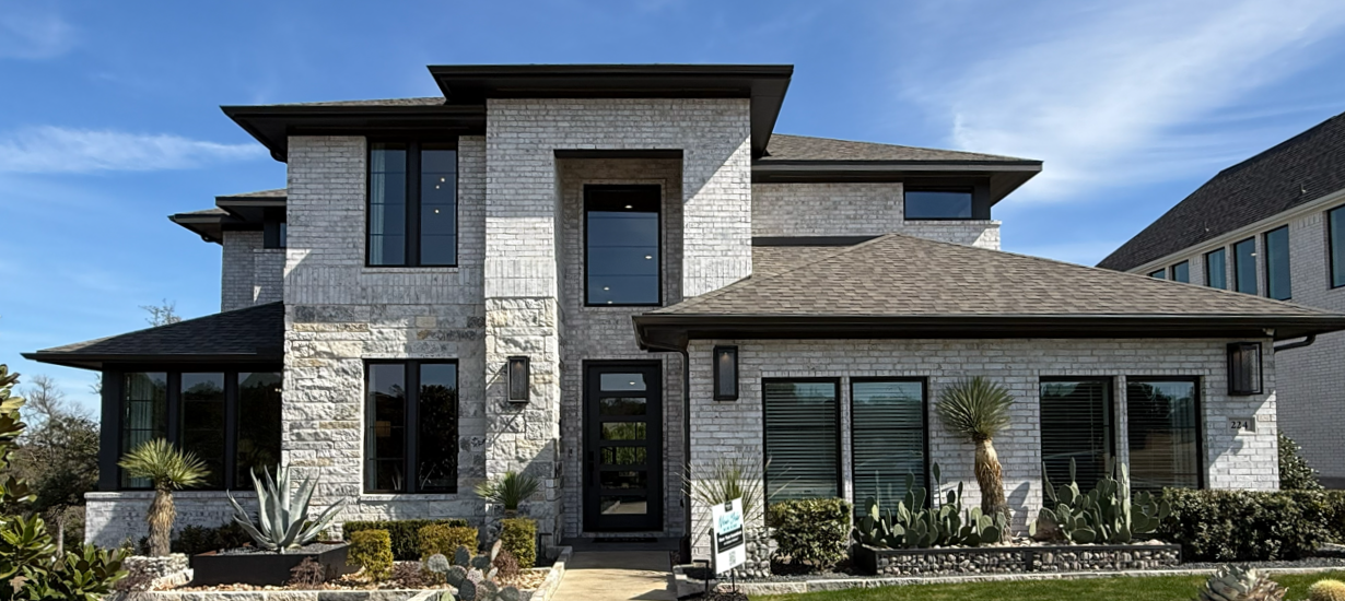 Modern home exterior with wooden front door, large windows, and landscaped entrance at dusk
