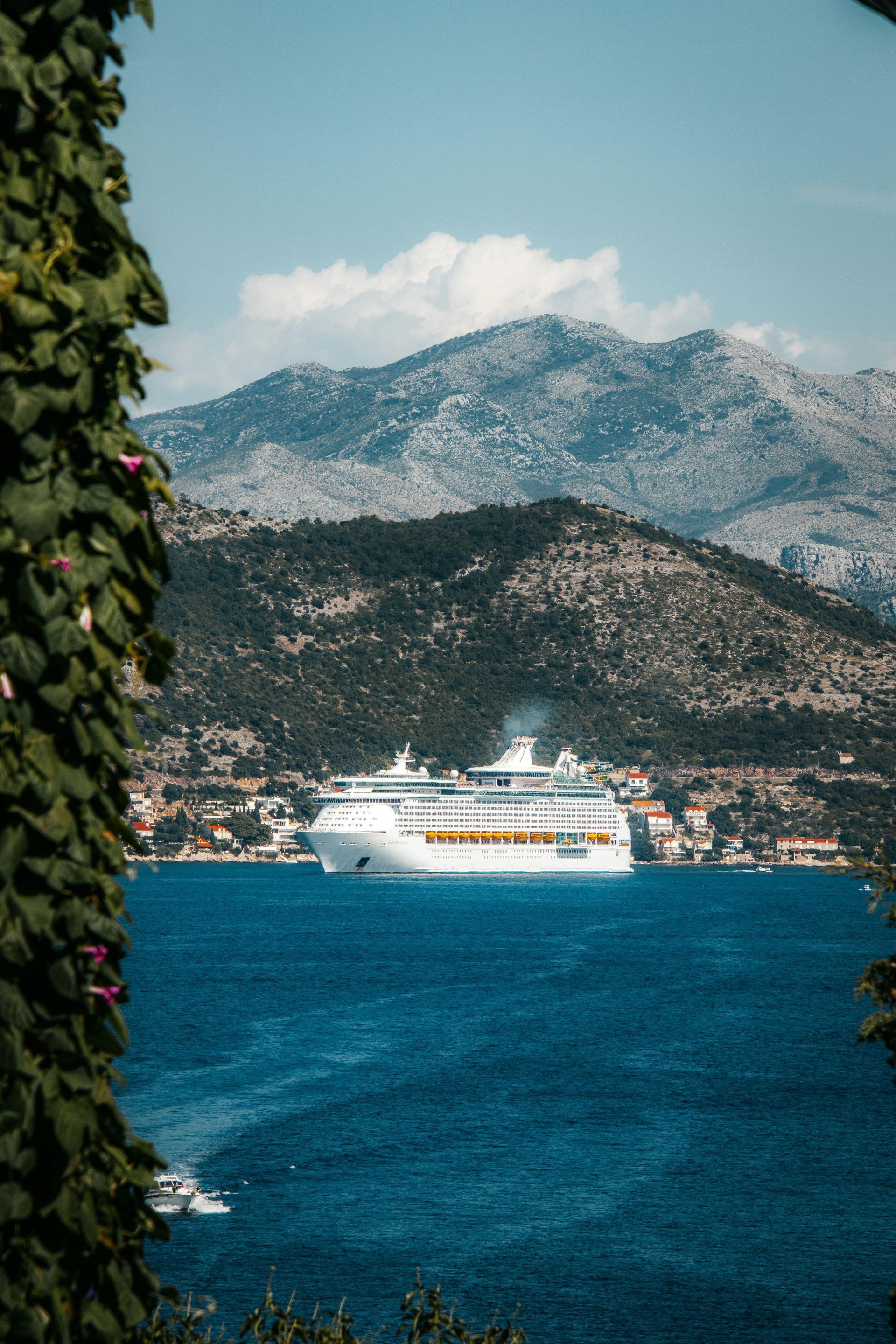A cruise ship is floating on top of a body of water with mountains in the background.