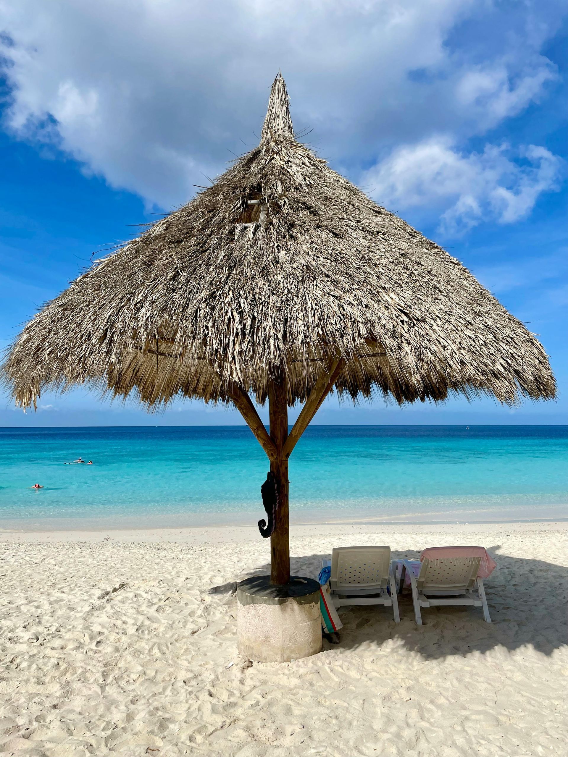 A thatched umbrella is sitting on top of a sandy beach.