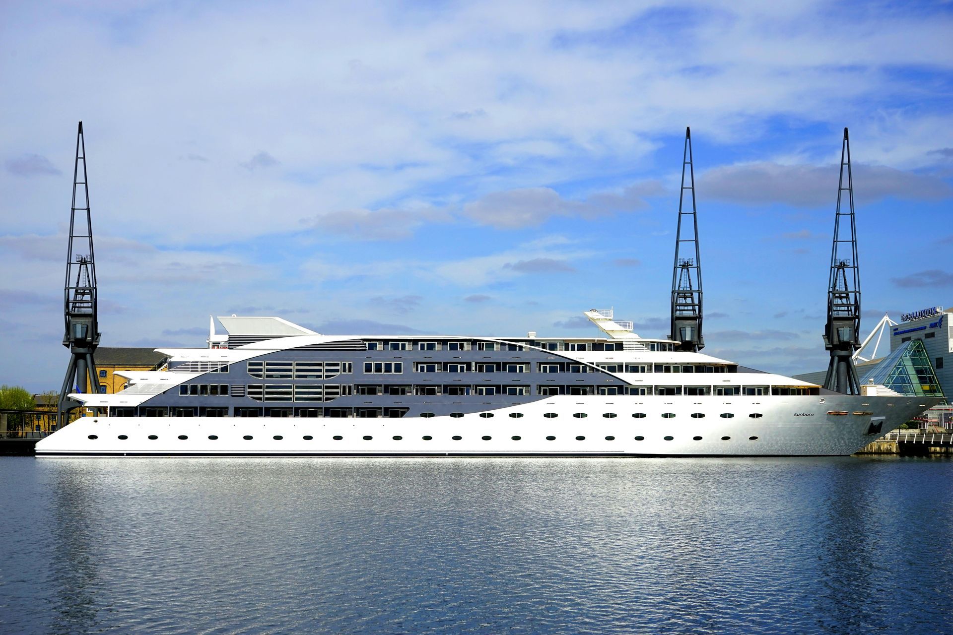 A large white cruise ship is docked in a harbor