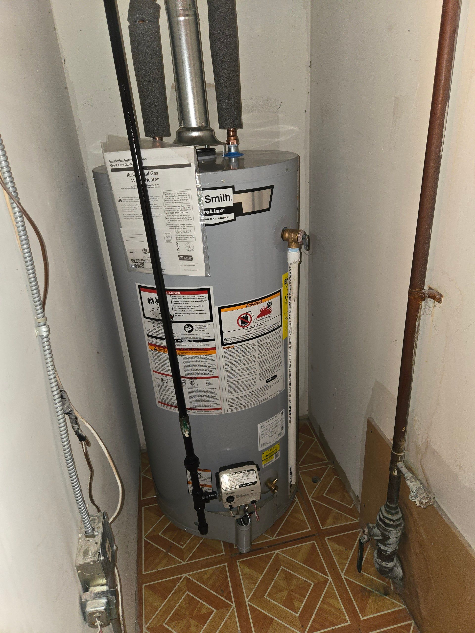 A water heater is sitting next to a furnace in a basement.