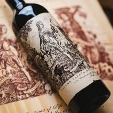 Botella de vino oscuro con etiqueta ornamentada sobre un fondo de mapa ilustrado en tono sepia.