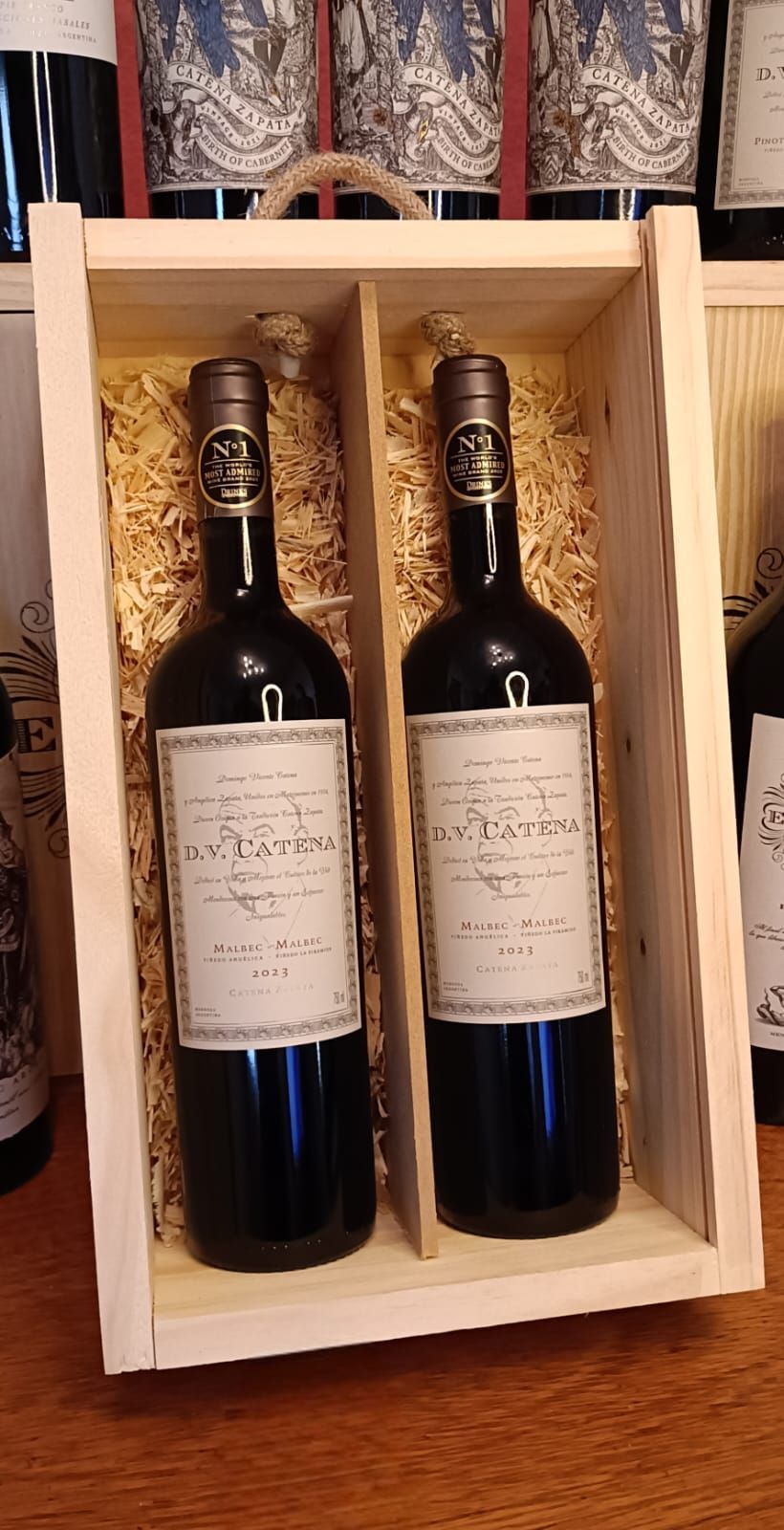 Dos botellas de vino en una caja de regalo de madera clara con separadores y etiquetas color crema.