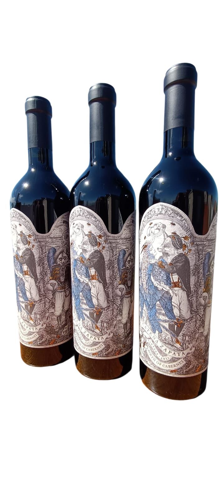 Tres botellas de vino oscuro con etiquetas abstractas ornamentadas sobre un fondo blanco.