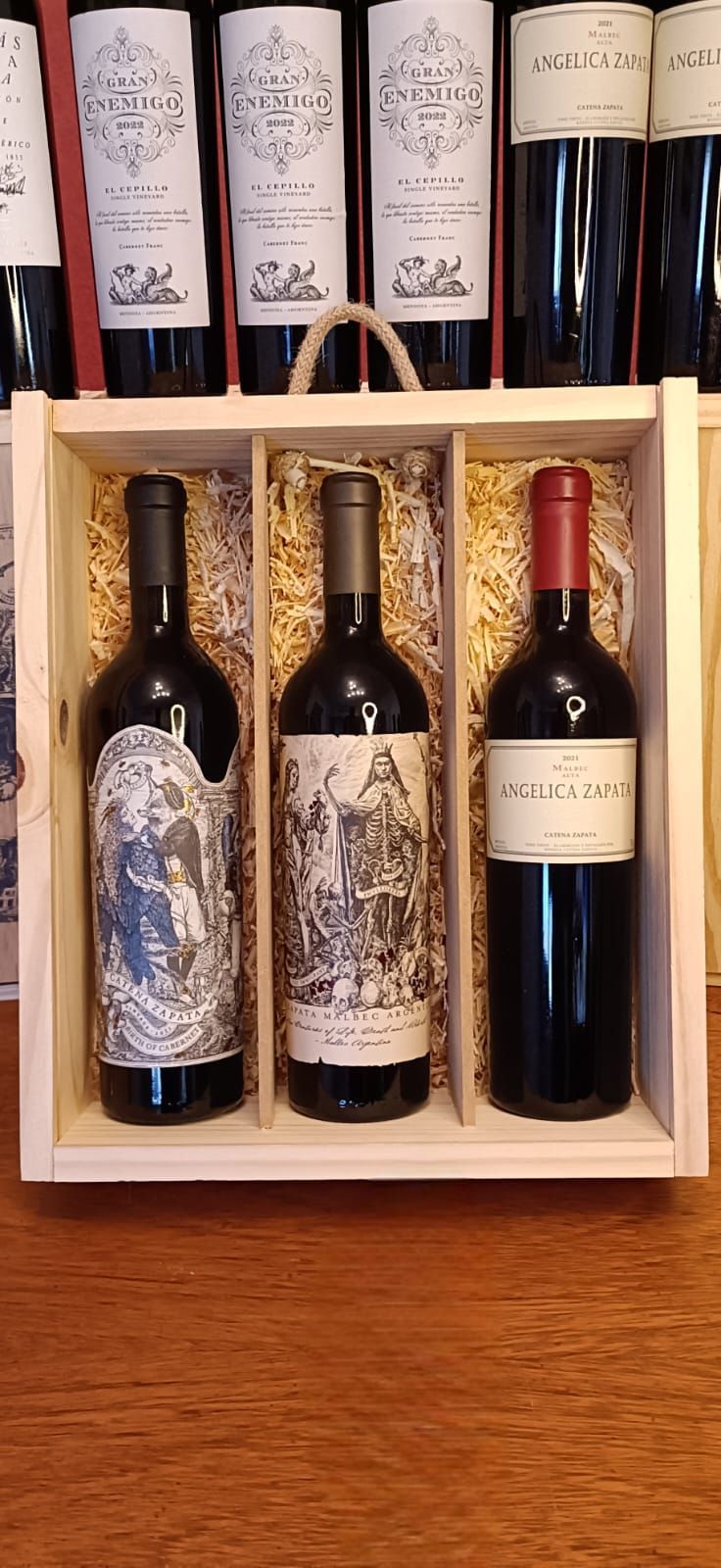 Caja de regalo de madera para vino con seis botellas de vino tinto sobre una mesa.