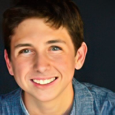 A young boy is smiling and wearing a blue shirt