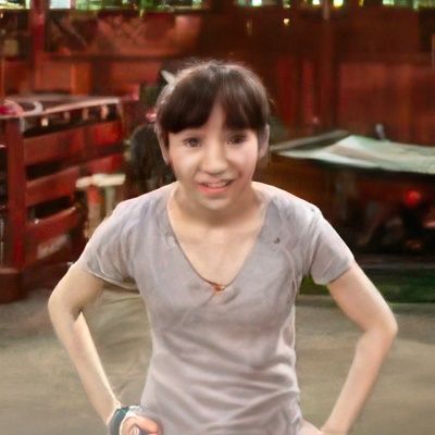 A girl in a grey shirt is standing with her hands on her hips