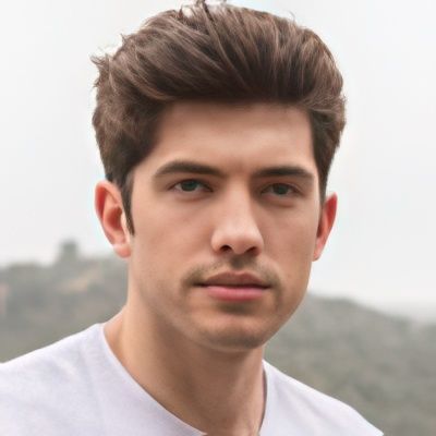 A young man in a white shirt is looking at the camera.