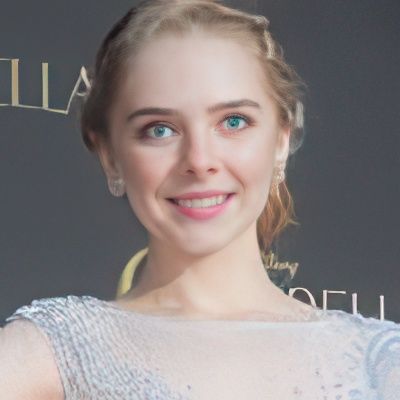 A woman is smiling in front of a sign that says illa
