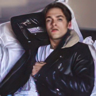 A man in a leather jacket is laying in a coffin