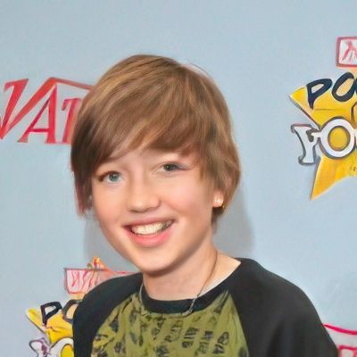 A young boy smiles in front of a sign that says variety