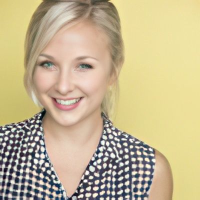 A woman wearing a plaid shirt is smiling for the camera