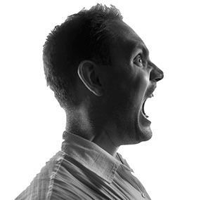 A man is screaming with his mouth open in a black and white photo.