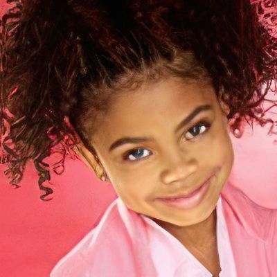 A little girl with curly hair is wearing a pink shirt