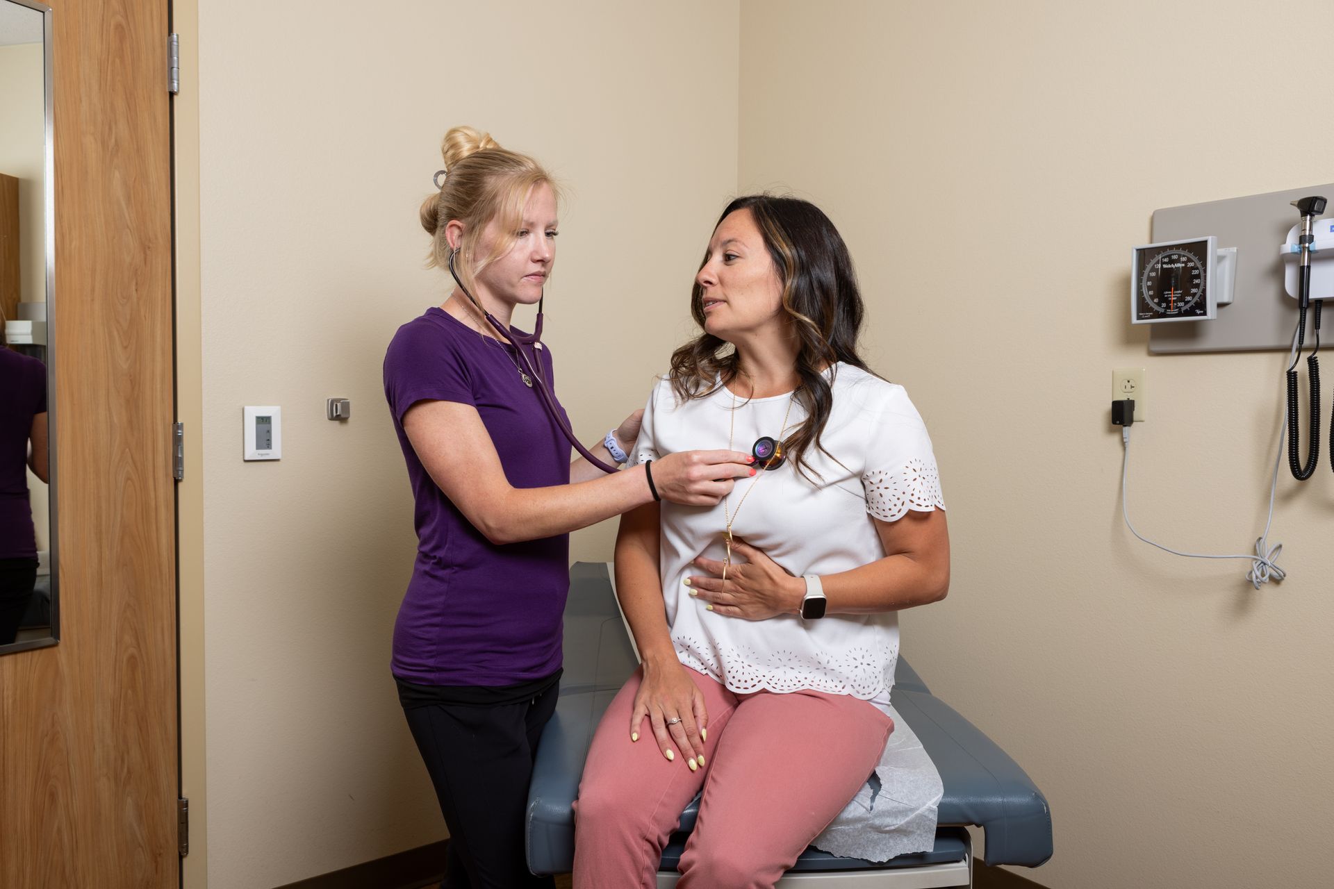 Doctor using a pulse oximeter on a patient's finger in a medical setting.