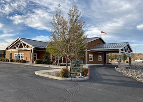 Medical clinic with a brown facade, a covered entrance, and a sign in front.