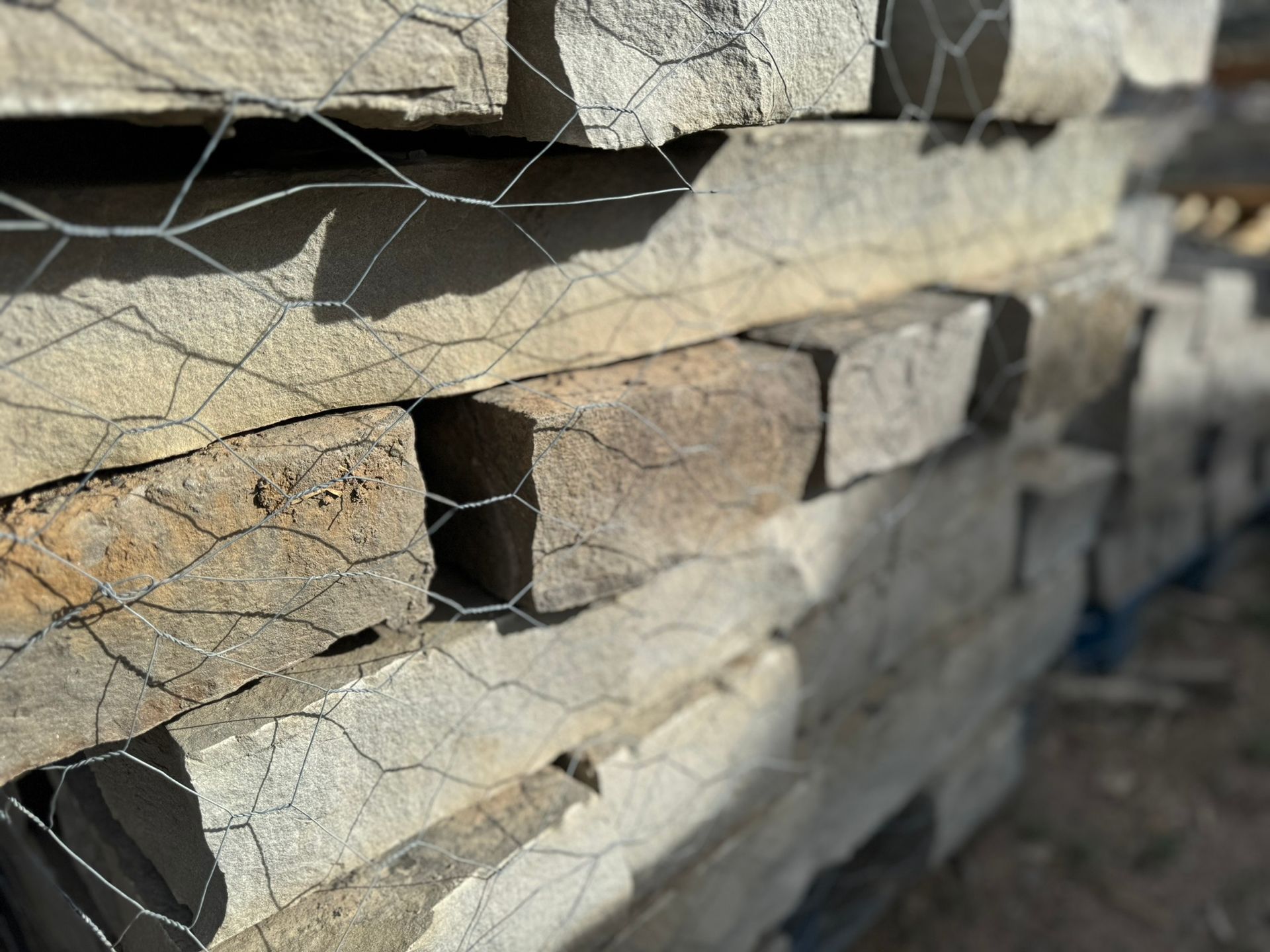 A pile of bricks stacked on top of each other behind a chain link fence.