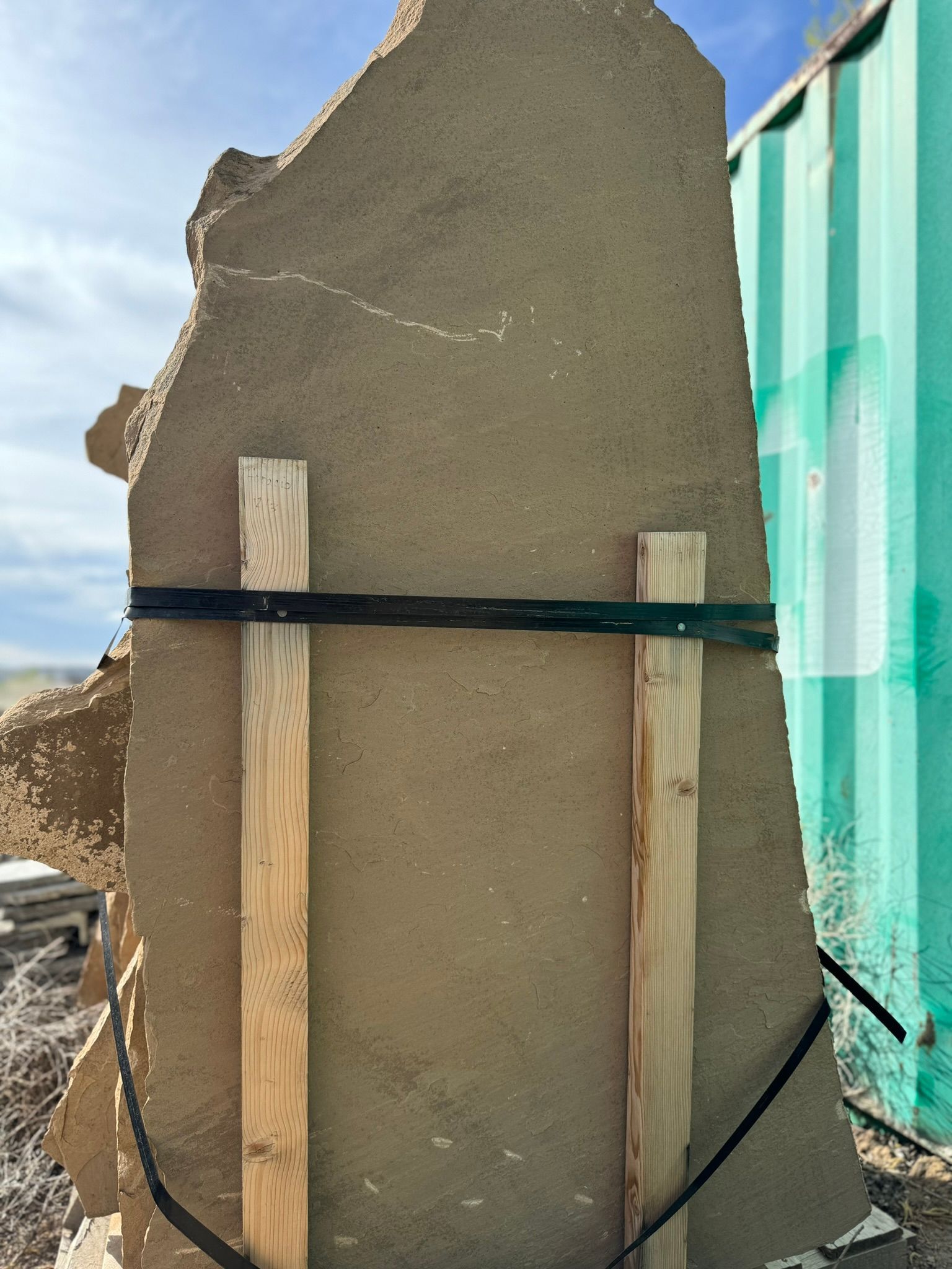 A large rock is tied to a green container with wooden slats