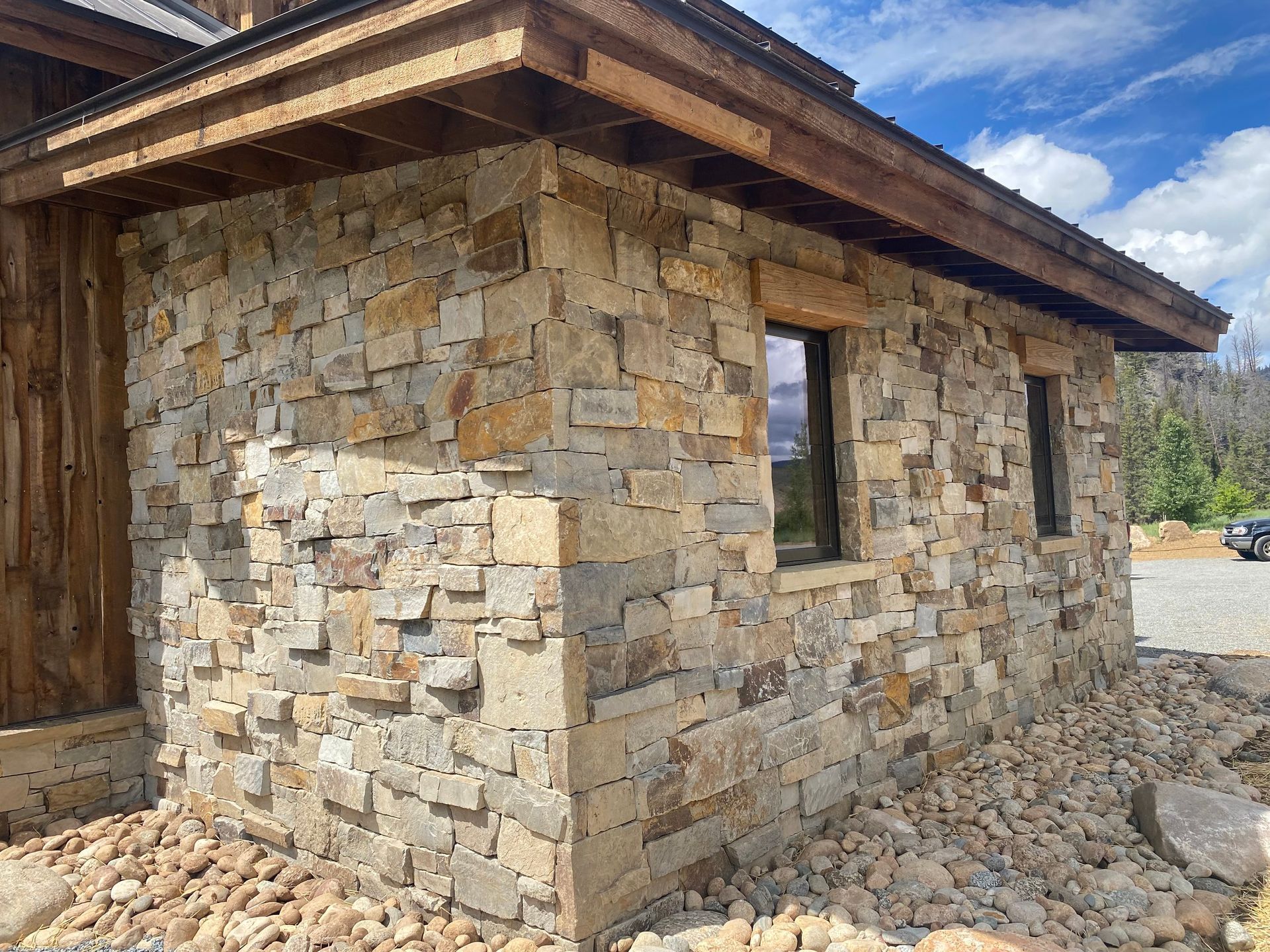 a stone building with two windows and a wooden roof .