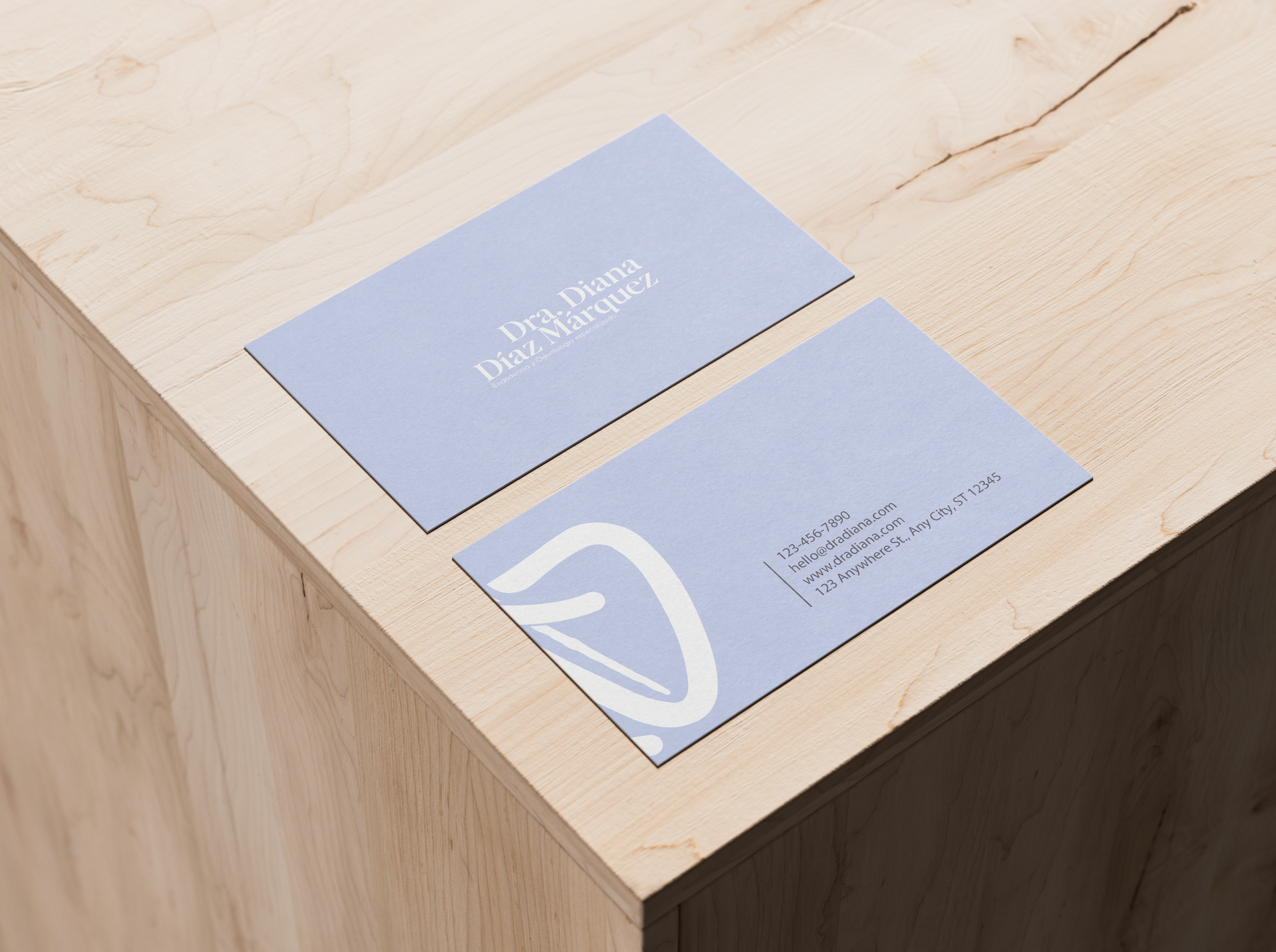 Dos tarjetas de visita azules sobre una mesa de madera clara; una de ellas muestra un logotipo y texto en blanco.