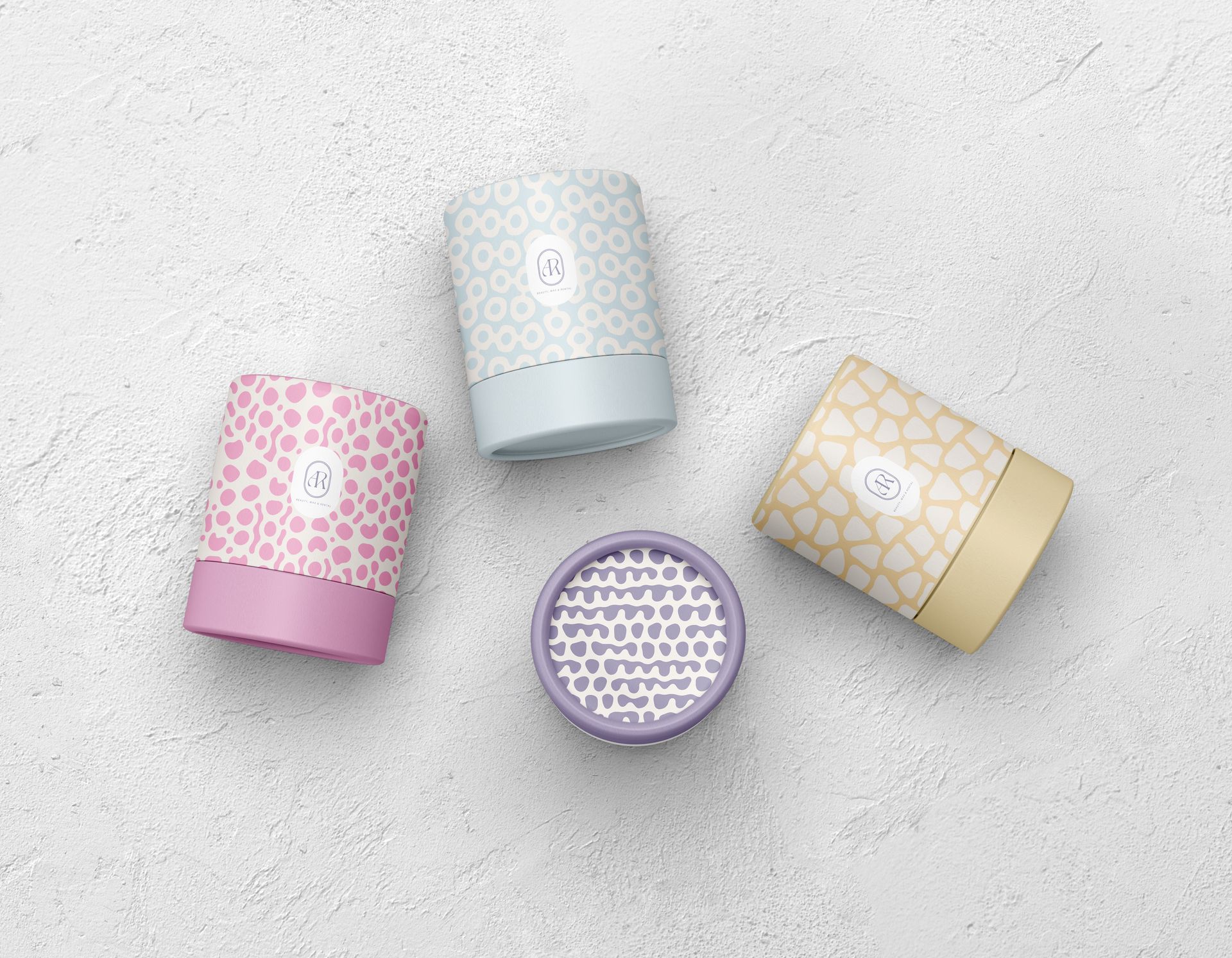 Cuatro tarros de cosméticos estampados en rosa, blanco, dorado y morado sobre una superficie gris claro.