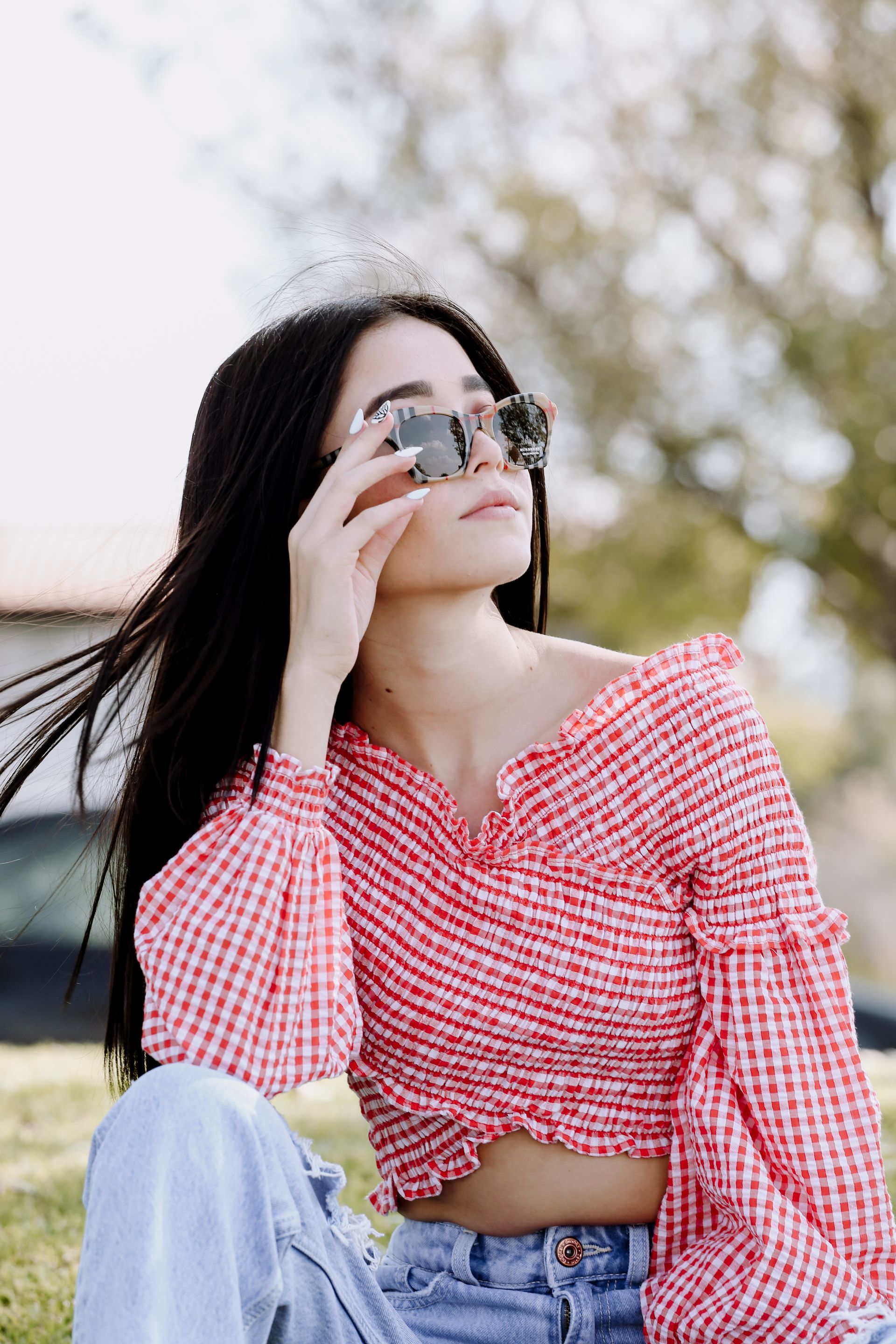 Mujer con blusa de cuadros rojos mirando a través de binoculares al aire libre.