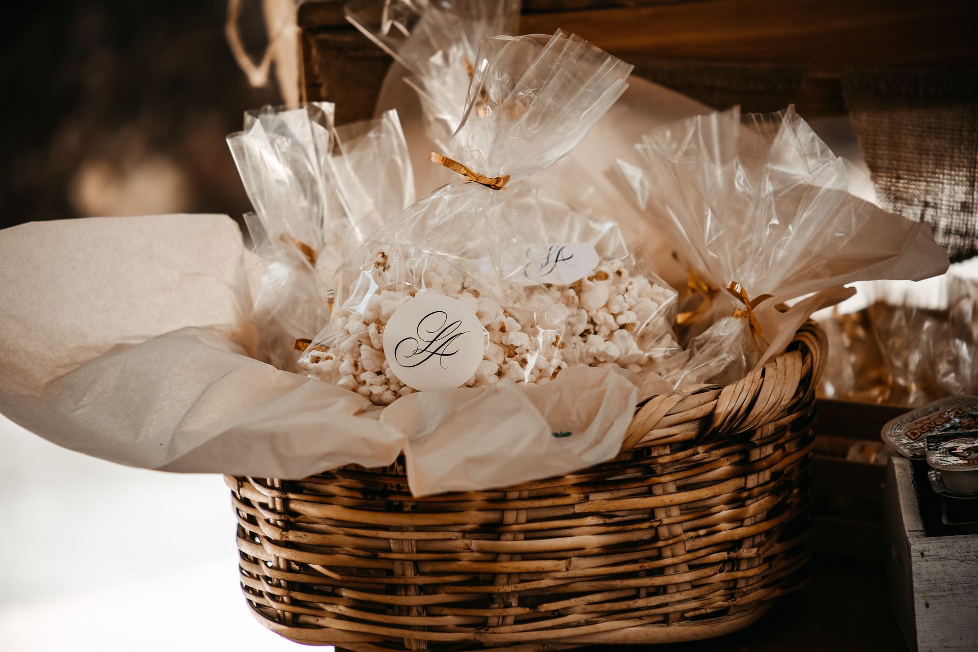 Cesta de regalo envuelta en celofán transparente con flores blancas y papel de seda en una cesta tejida.
