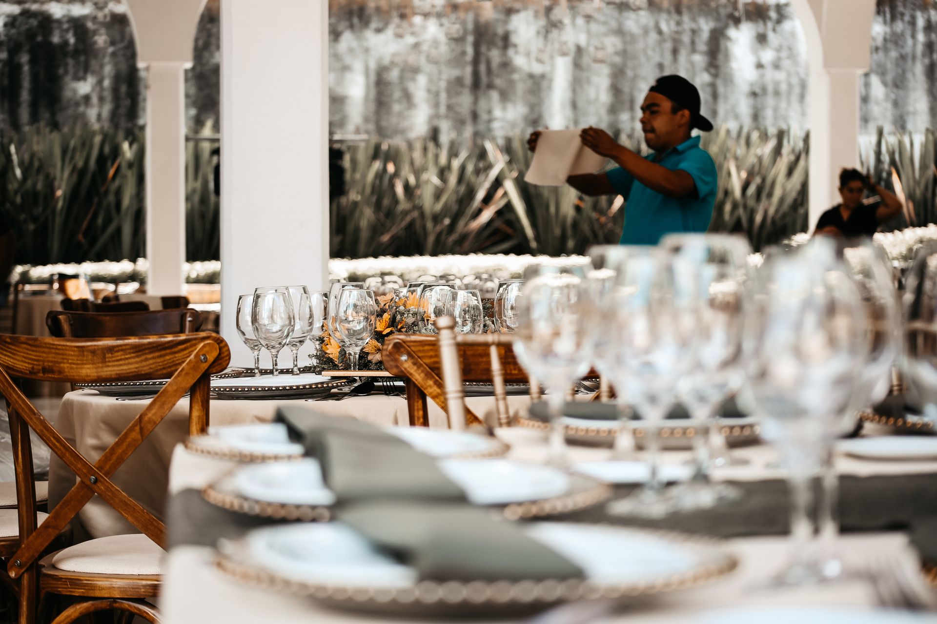 Una persona lee un menú en un comedor luminoso y bien equipado, con mesas blancas y sillas de mimbre.