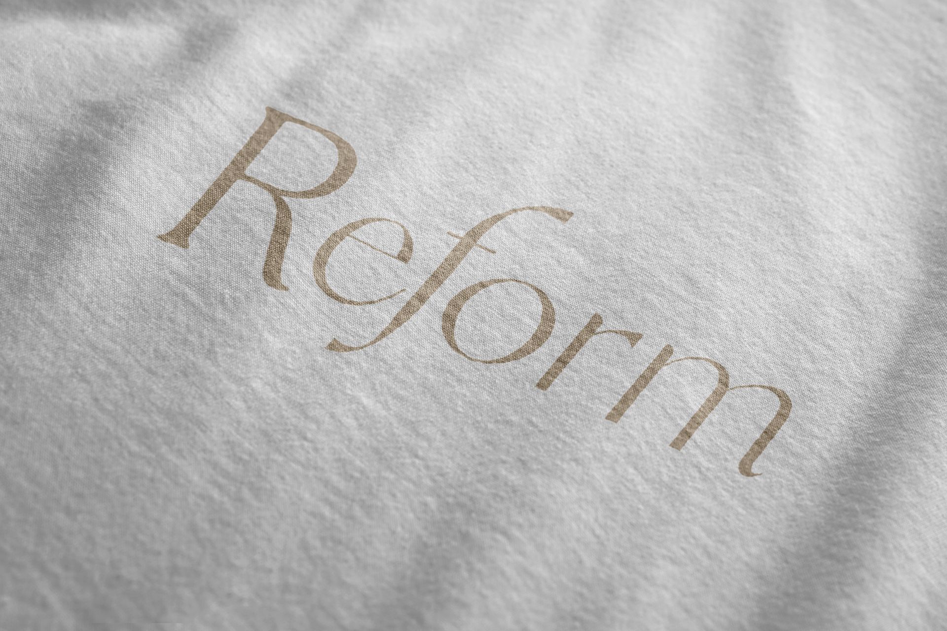 Texto “Reforma” en relieve dorado sobre tela blanca suave.